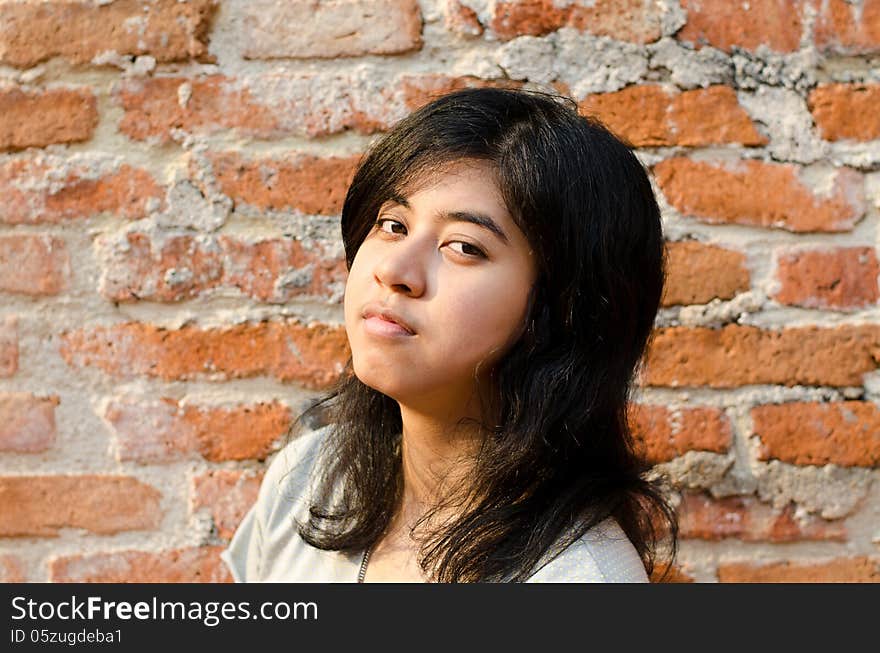 Pretentious asian girl over brick wall. Pretentious asian girl over brick wall