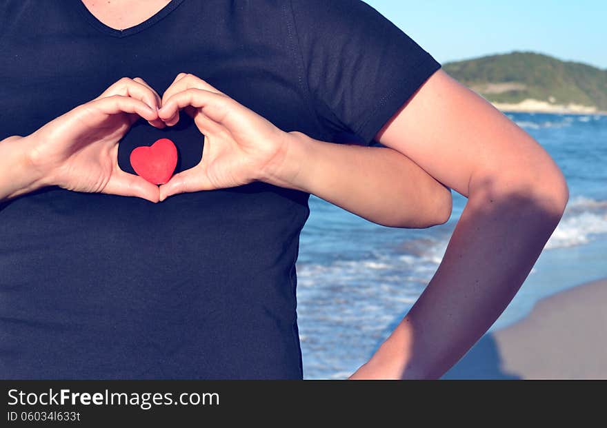 Heart shape of hands by the beach