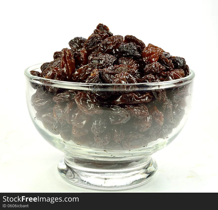 A glass bowl of raisins on a white background.