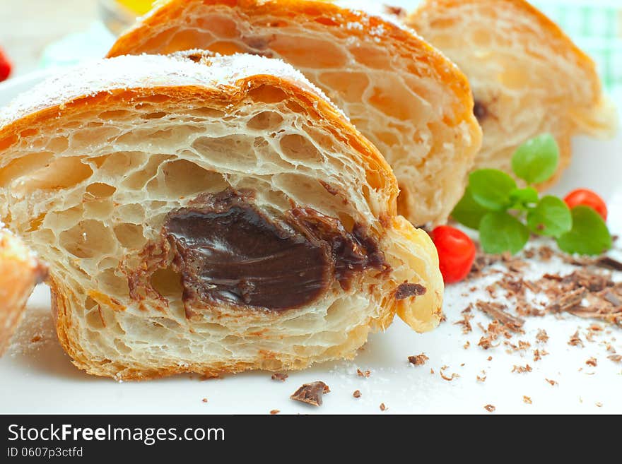 Roll with chocolate cream on a plate decorated with chocolate crumbs, herbs and berries, closeup. Roll with chocolate cream on a plate decorated with chocolate crumbs, herbs and berries, closeup