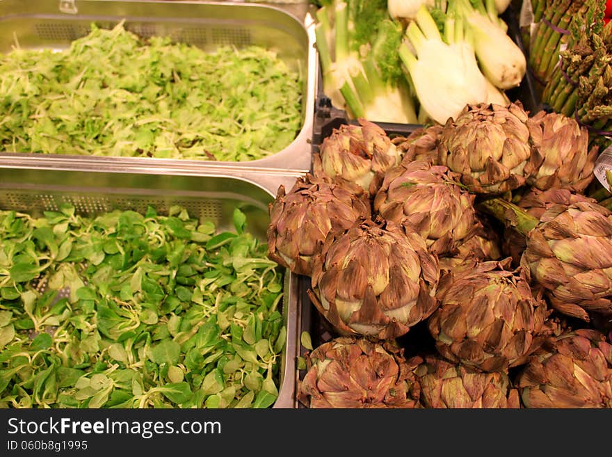 Artichoke and salad placed in stainless steel containers in supermarket