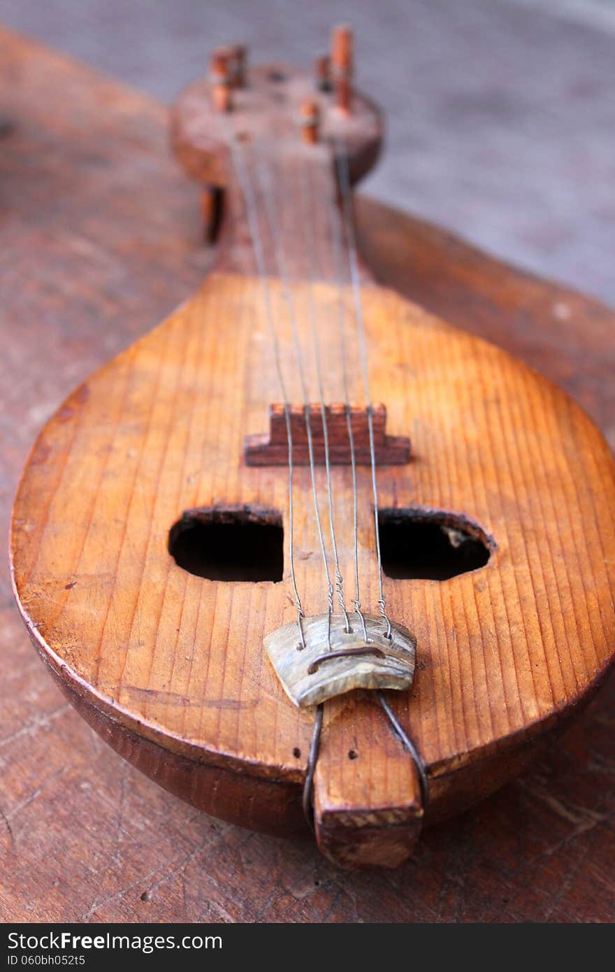 Antique old-fashioned obsolete mandolin on wooden table. Antique old-fashioned obsolete mandolin on wooden table