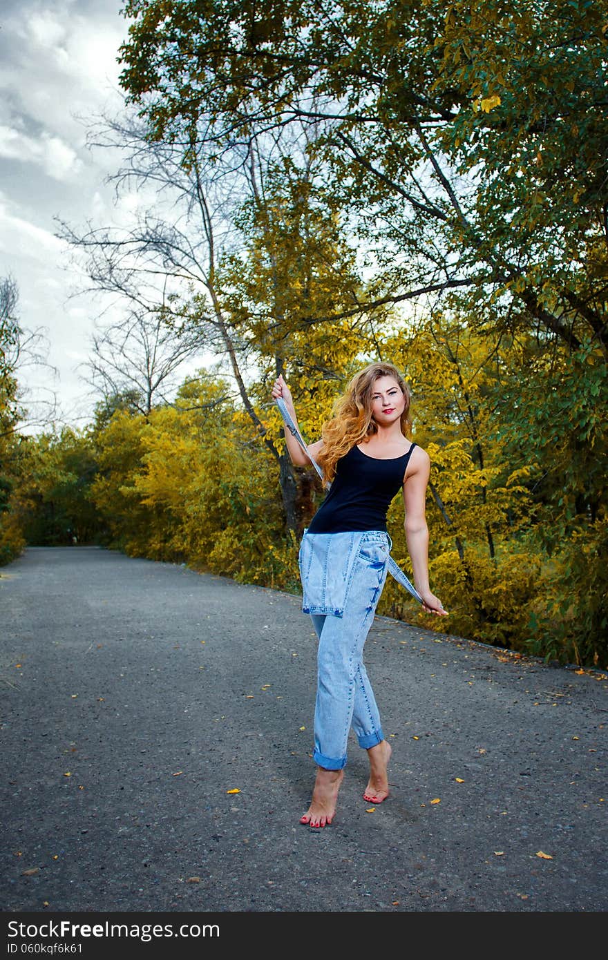 Beautiful pin-up girl in denim overalls and a T-shirt outdoors