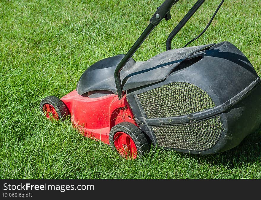 Modern lawn mower on a green lawn. Mowing the lawn with an electric mower with a container to collect the cut grass.