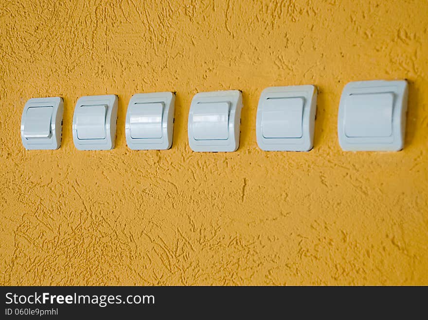 Row of white electric switches on the orange wall