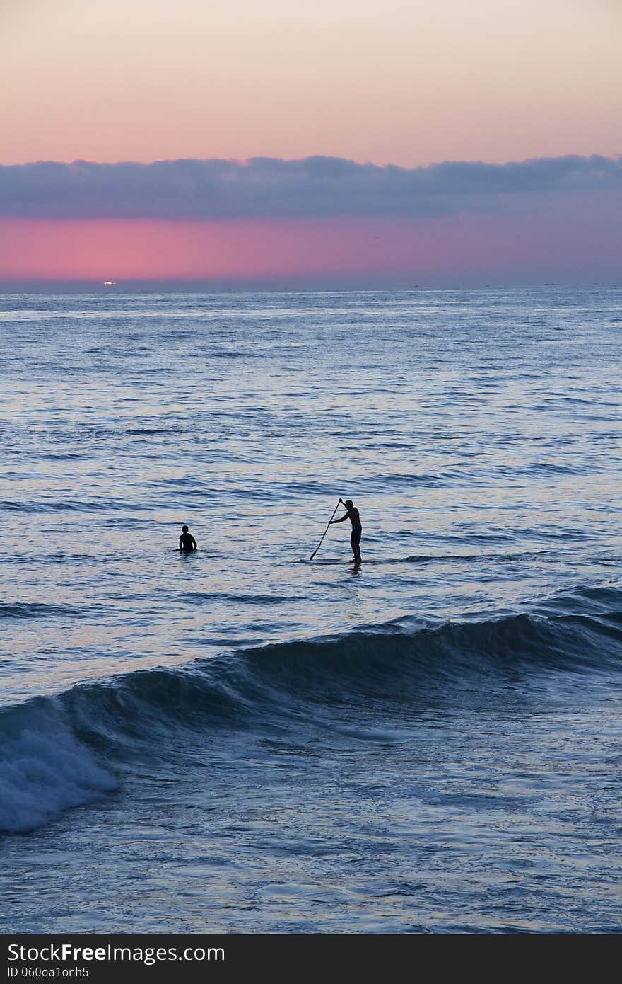 Silhouette of a surfer and paddle-boarder watching the sunset. Silhouette of a surfer and paddle-boarder watching the sunset.