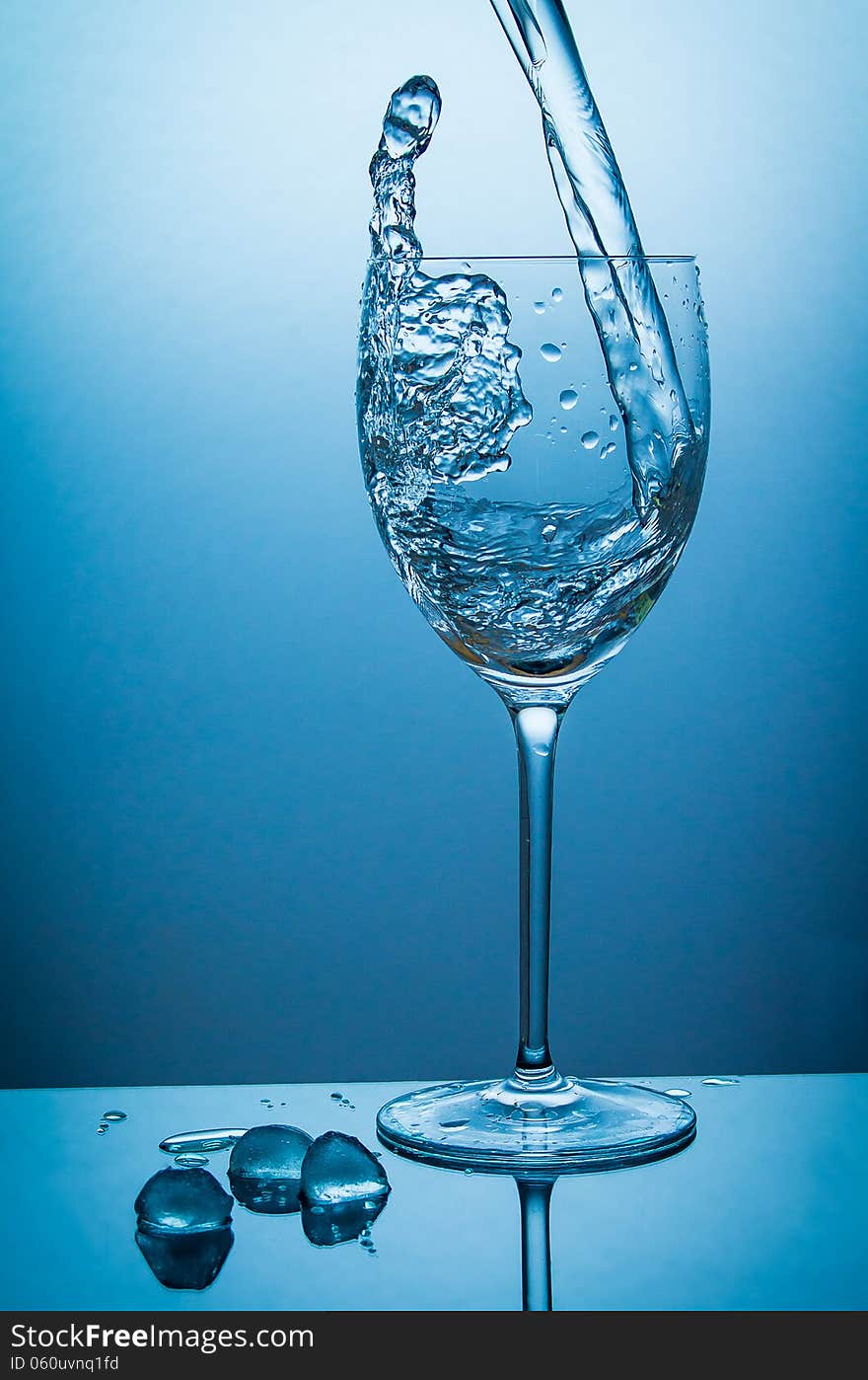 Water being poured in a wine-glass too fast, water jumps out of the glass again. Water being poured in a wine-glass too fast, water jumps out of the glass again