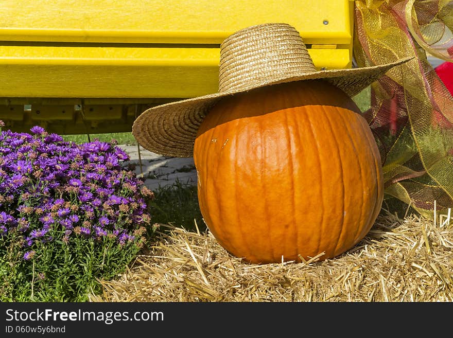 Pumpkin and hat on hay with flowers