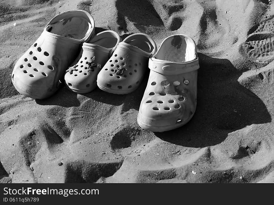 An adult and child rubber saddles on the sand in black and white. An adult and child rubber saddles on the sand in black and white.