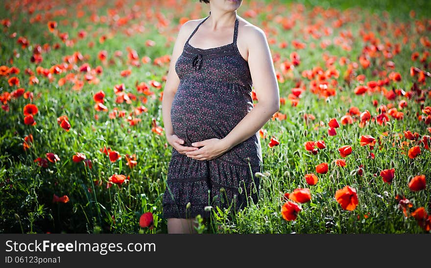 Pregnant happy woman in a flowering poppy field outdoors