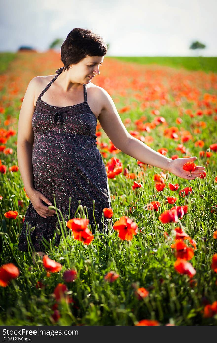 Pregnant happy woman in a flowering poppy field outdoors