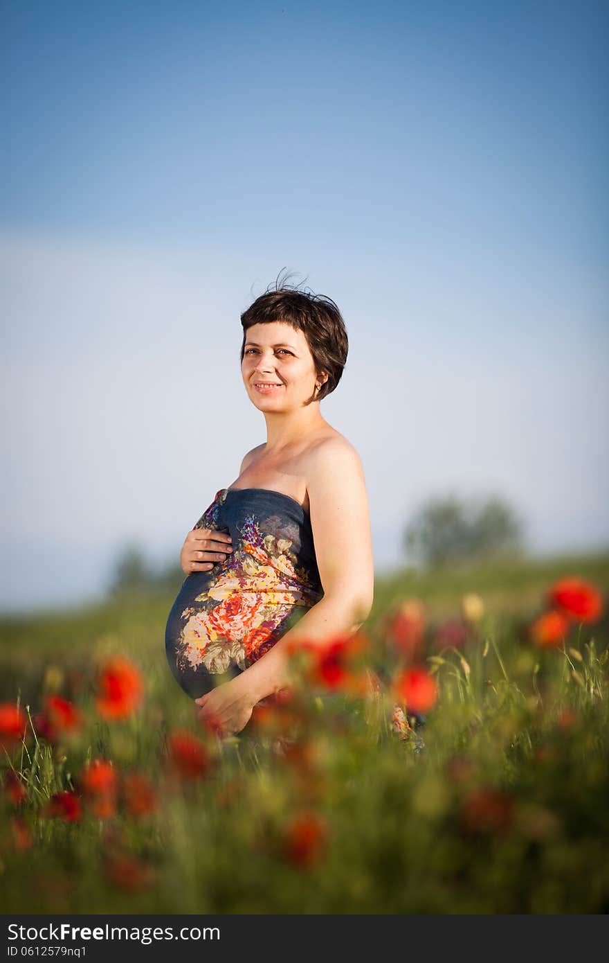 Pregnant happy woman in a flowering poppy field outdoors