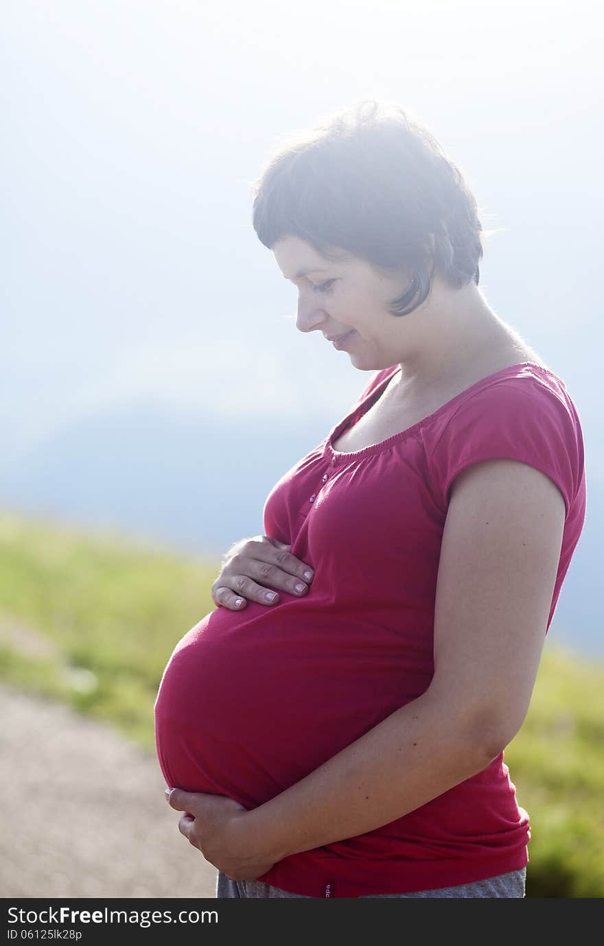 Pregnant happy woman in a flowering poppy field outdoors