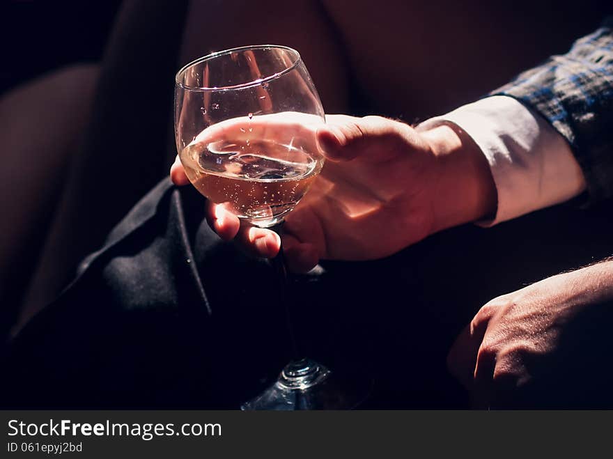 Man in a suit holding his hand a glass of champagne while sitting in a limousine. Man in a suit holding his hand a glass of champagne while sitting in a limousine