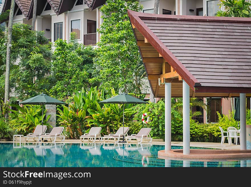 Couches with umbrellas around swimming pool in the resort