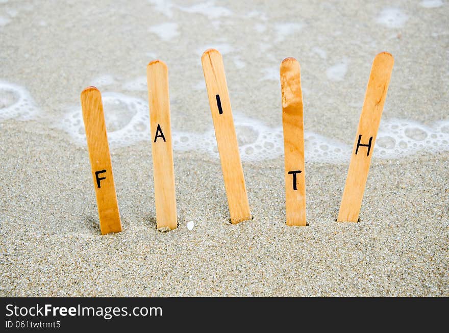 Faith text on wood pin on the sand.