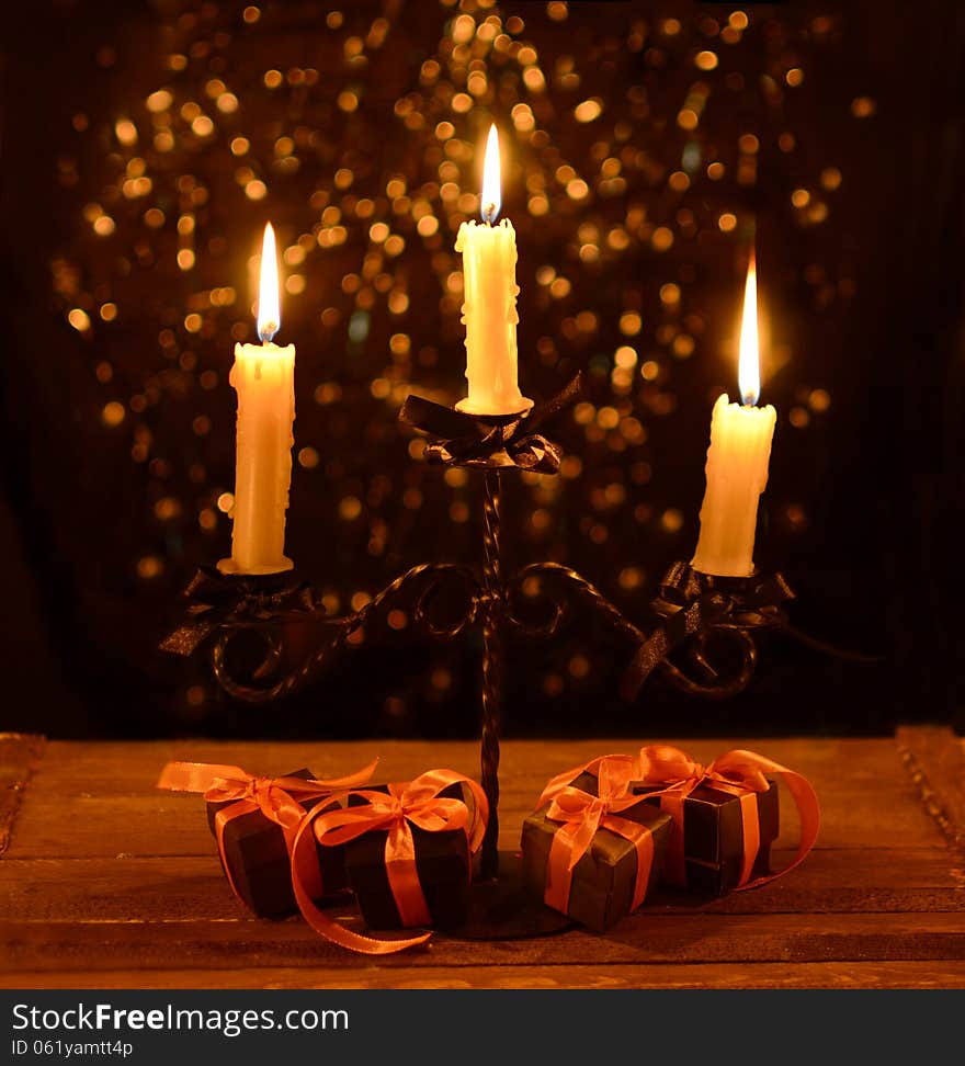 Candelabra with four Halloween gifts in black wrapping on the black shining background. Candelabra with four Halloween gifts in black wrapping on the black shining background