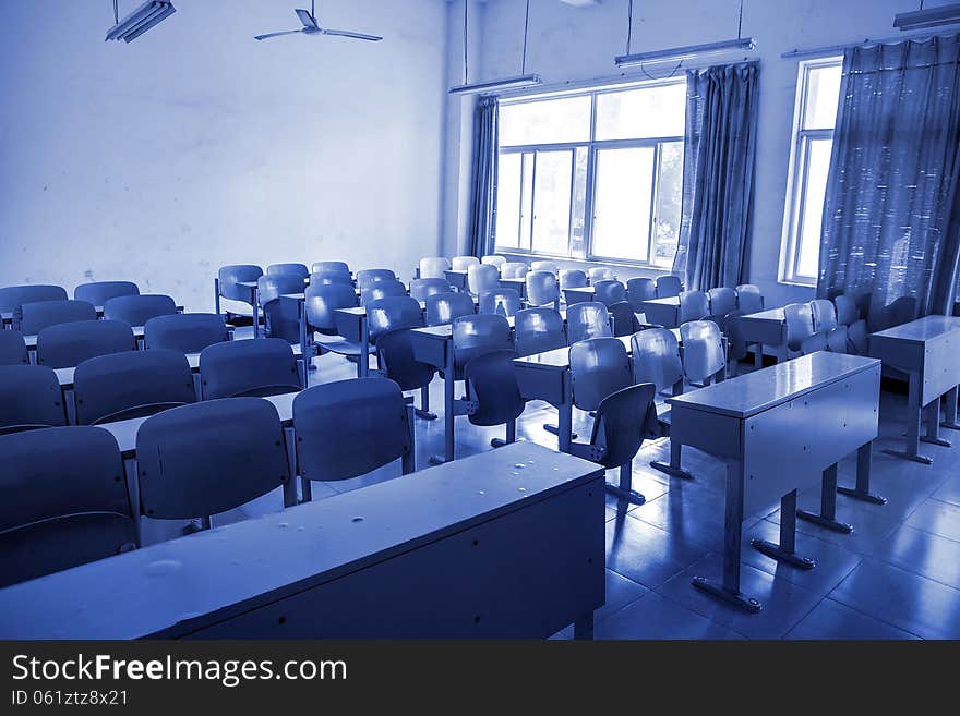 Neat rows of school desks in classroom with blue tones