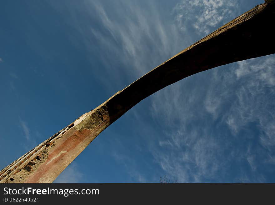 Arch of the old ruined building on a background of blue sky. Arch of the old ruined building on a background of blue sky