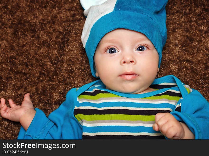 Blue-eyed baby lies on his back and smiling while looking at the camera