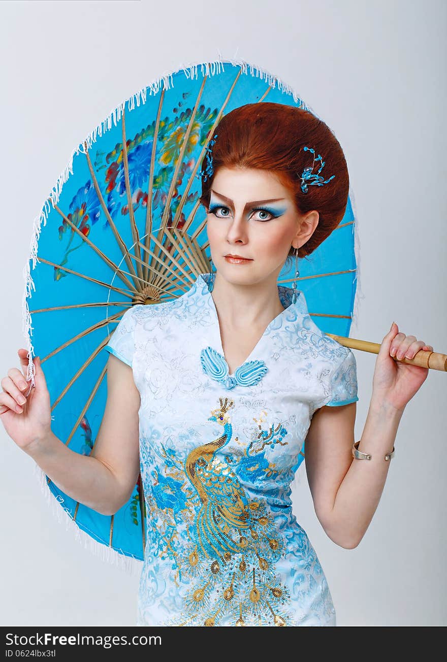 Attractive geisha in a smart dress with an umbrella, photographed in the studio. Attractive geisha in a smart dress with an umbrella, photographed in the studio