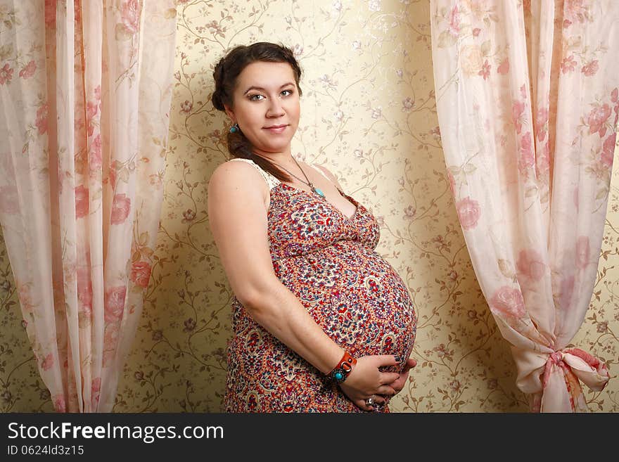 Beautiful pregnant girl on a large stage of pregnancy photographed in the studio