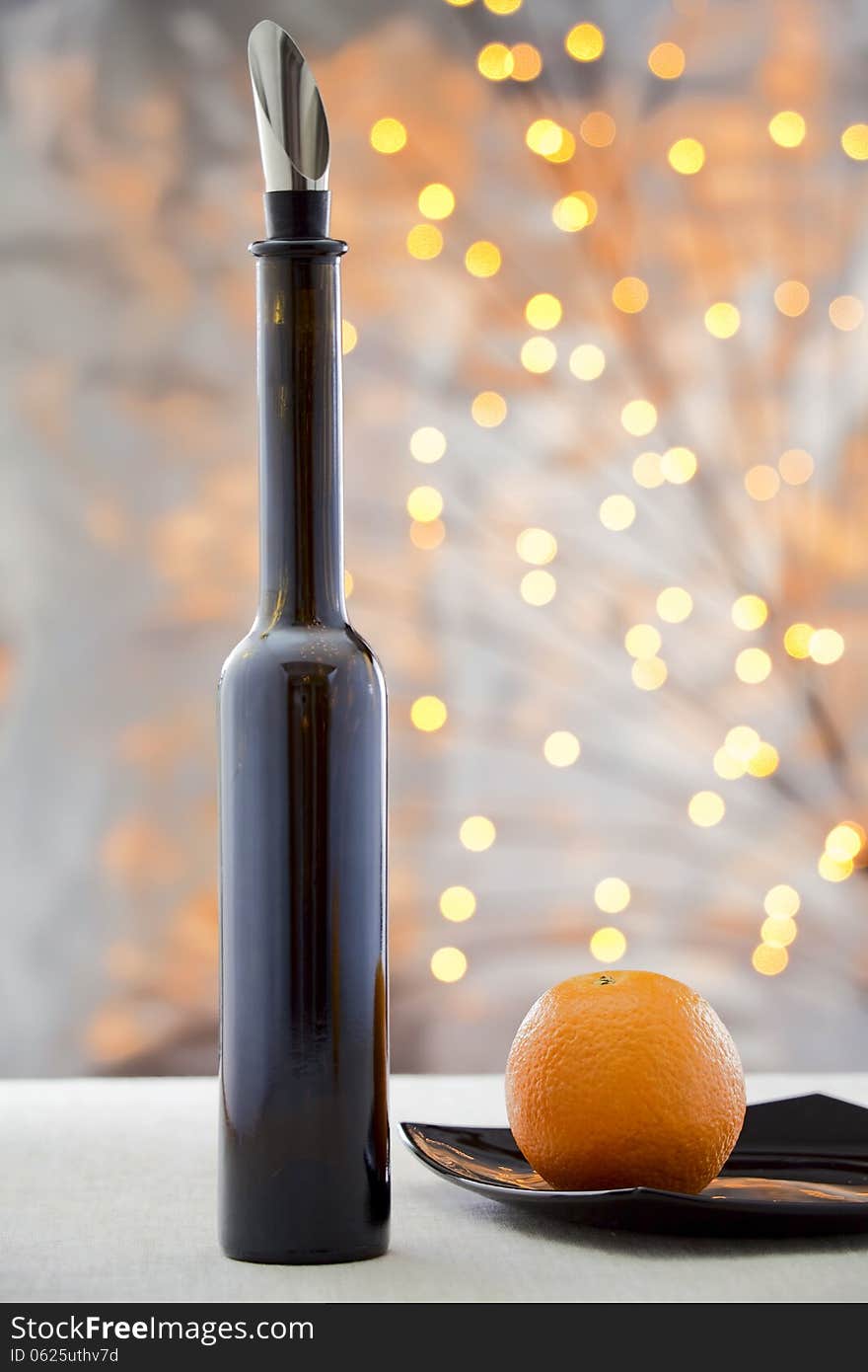 Orange on the plate and a bottle of wine on a multicolored background. Orange on the plate and a bottle of wine on a multicolored background