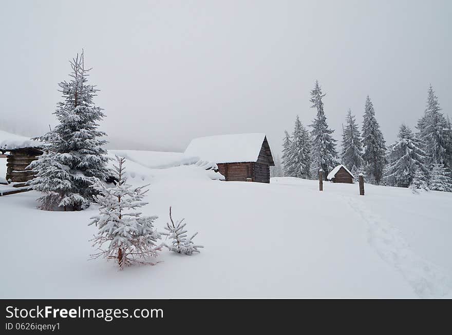 Wooden cabins in a mountain valley. Winter landscape. Ukraine, Carpathians. Wooden cabins in a mountain valley. Winter landscape. Ukraine, Carpathians