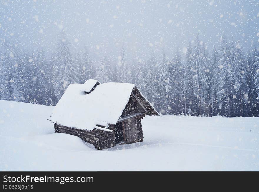 Winter landscape with hut in a mountain forest. Blizzard overcast day. Winter landscape with hut in a mountain forest. Blizzard overcast day