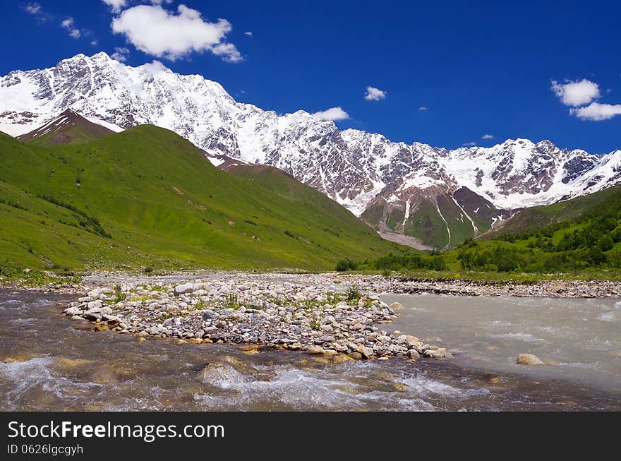 Mountain river in a valley. Shkhara Ridge Mountains, Georgia, Caucasus. Mountain river in a valley. Shkhara Ridge Mountains, Georgia, Caucasus