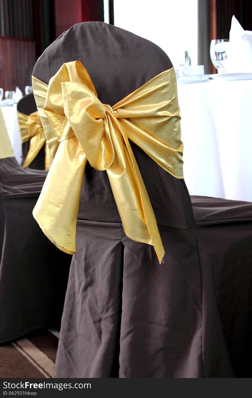 Brown wedding chairs decorated with golden bows. Brown wedding chairs decorated with golden bows