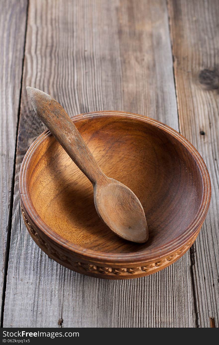 Wooden spoon and a bowl on a wooden background. Wooden spoon and a bowl on a wooden background