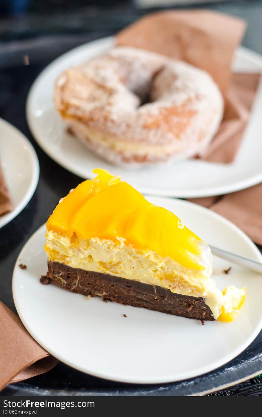 Mango cake and donuts in a coffee shop- closeup. Mango cake and donuts in a coffee shop- closeup