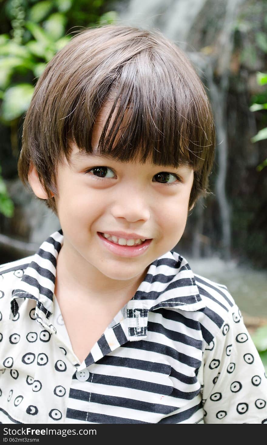 Little Asian boy smiling portrait with water fall background