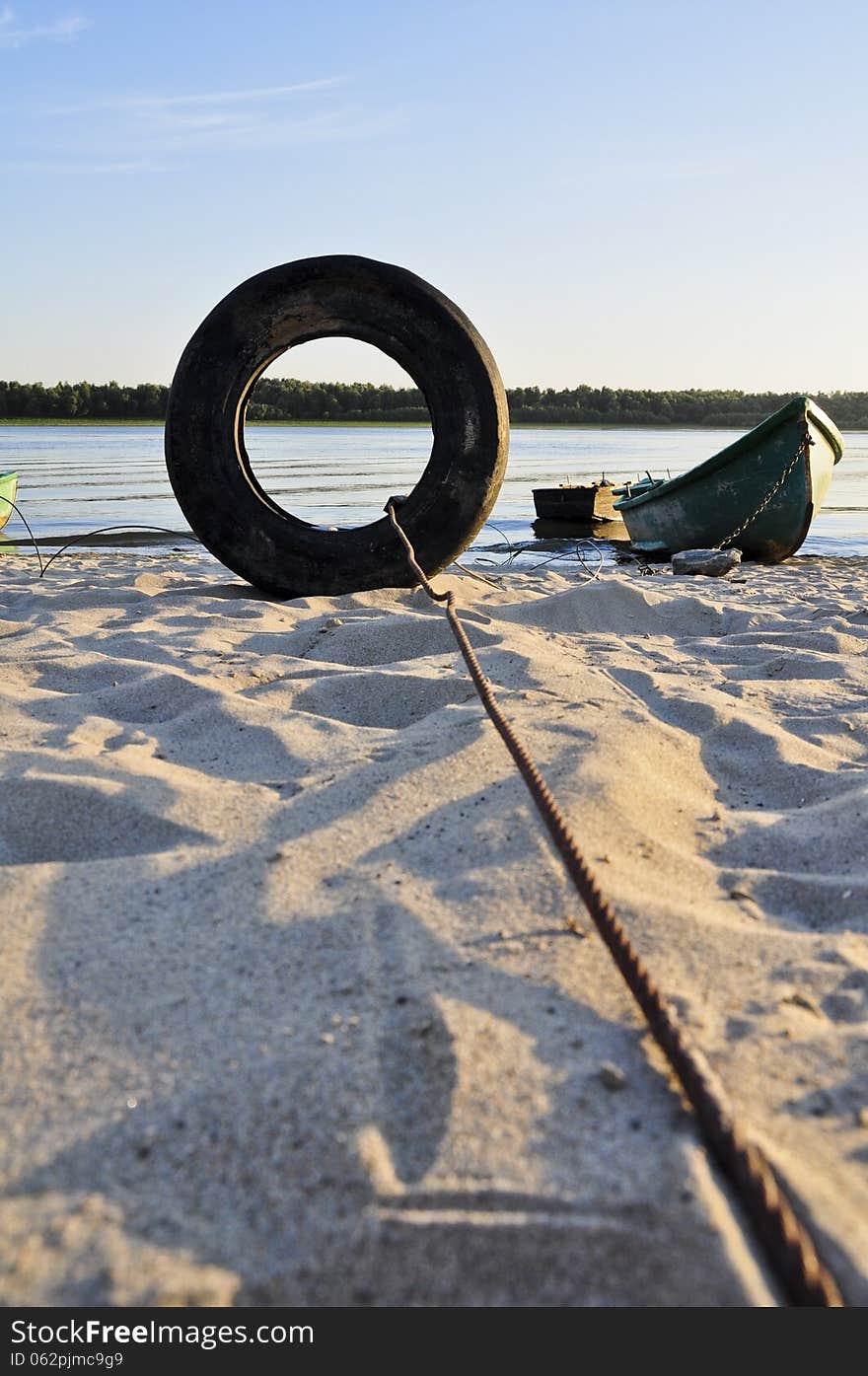 A fisherman boat, tied on Danube shore, through an old tire.