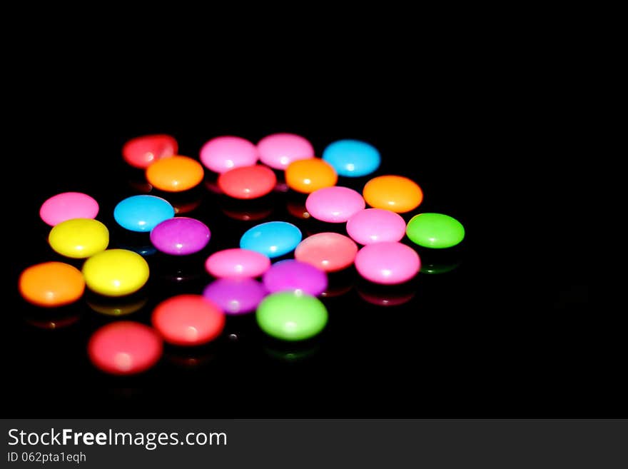 Many colorful chocolate candies against a black background