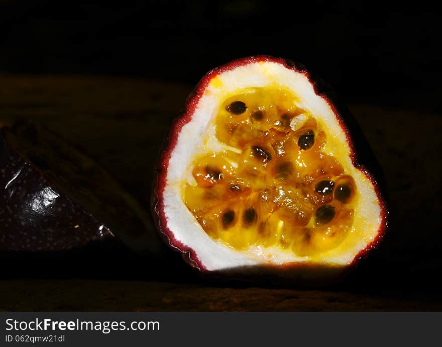 An organically grown passionfruit from tropical Queensland which has been cut into halves and is showing close up details of the bright yellow fleshy pulp and seeds of this very popular fruit. Passion fruit is used in many Australian deserts, puddings, cakes and also as a syrup and a topping. An organically grown passionfruit from tropical Queensland which has been cut into halves and is showing close up details of the bright yellow fleshy pulp and seeds of this very popular fruit. Passion fruit is used in many Australian deserts, puddings, cakes and also as a syrup and a topping.