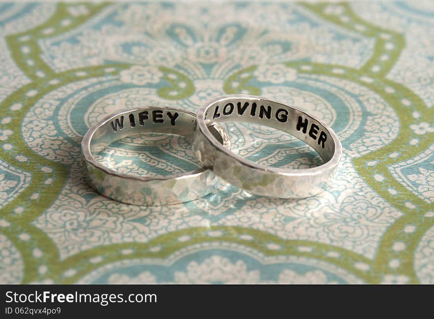 Two hammered sterling silver engagement rings on a piece of decorative paper. Two hammered sterling silver engagement rings on a piece of decorative paper