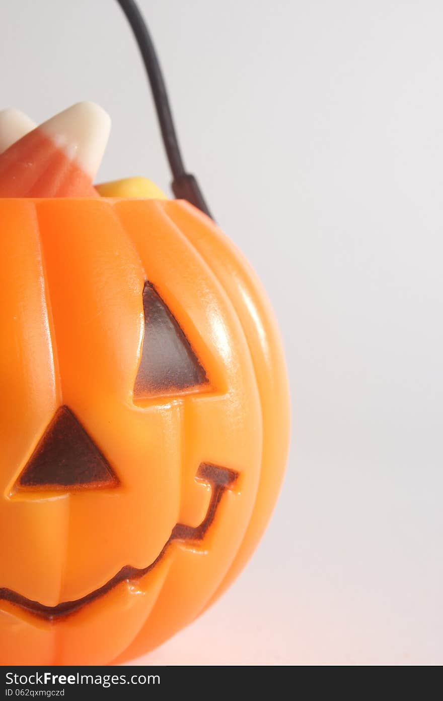 Macro of plastic pumpkin with a carved happy face and candy corn. Macro of plastic pumpkin with a carved happy face and candy corn