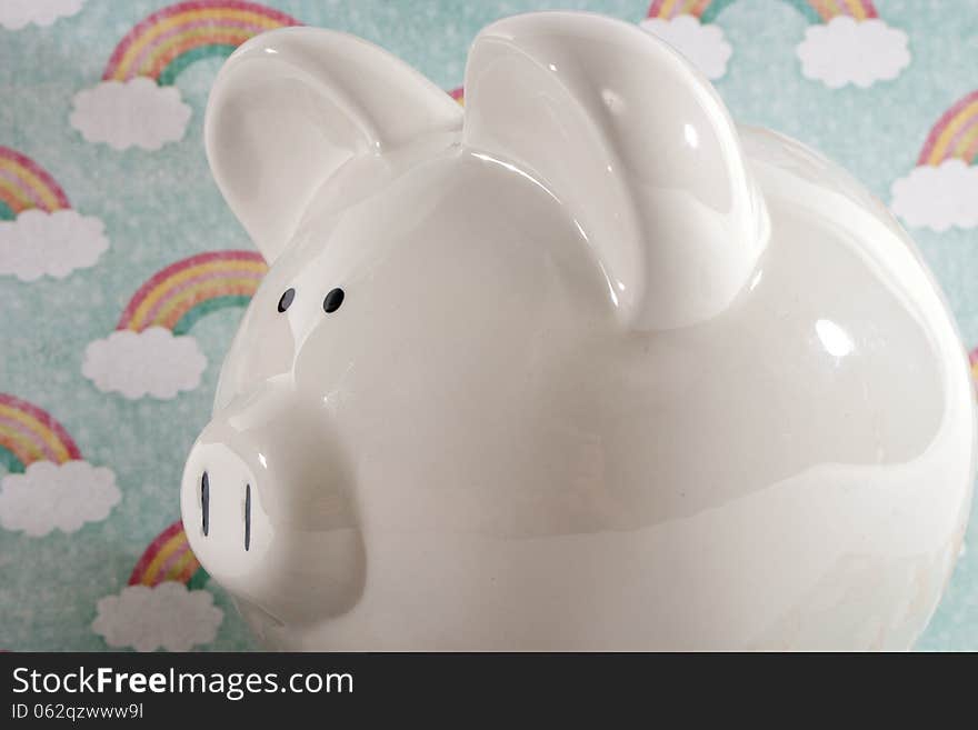 White ceramic piggy bank against a rainbow decorative background. White ceramic piggy bank against a rainbow decorative background