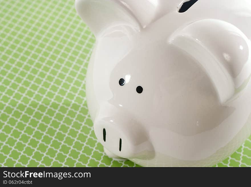 White ceramic piggy bank against a green decorative background. White ceramic piggy bank against a green decorative background