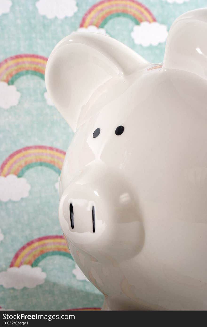 White ceramic piggy bank against a rainbow decorative background. White ceramic piggy bank against a rainbow decorative background