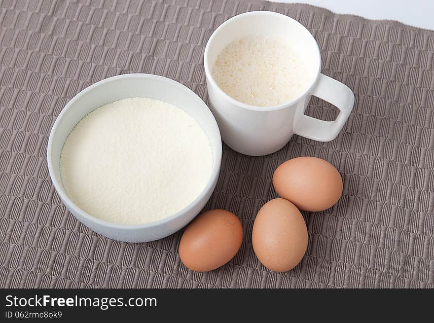 Dried albumin and eggs with dissolve albumin in a white cup on tablecloth. Dried albumin and eggs with dissolve albumin in a white cup on tablecloth.