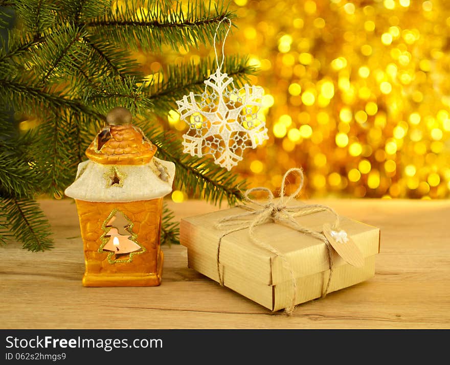 Yellow candle holder with gift in paper wrapping on the golden blurred background. Yellow candle holder with gift in paper wrapping on the golden blurred background