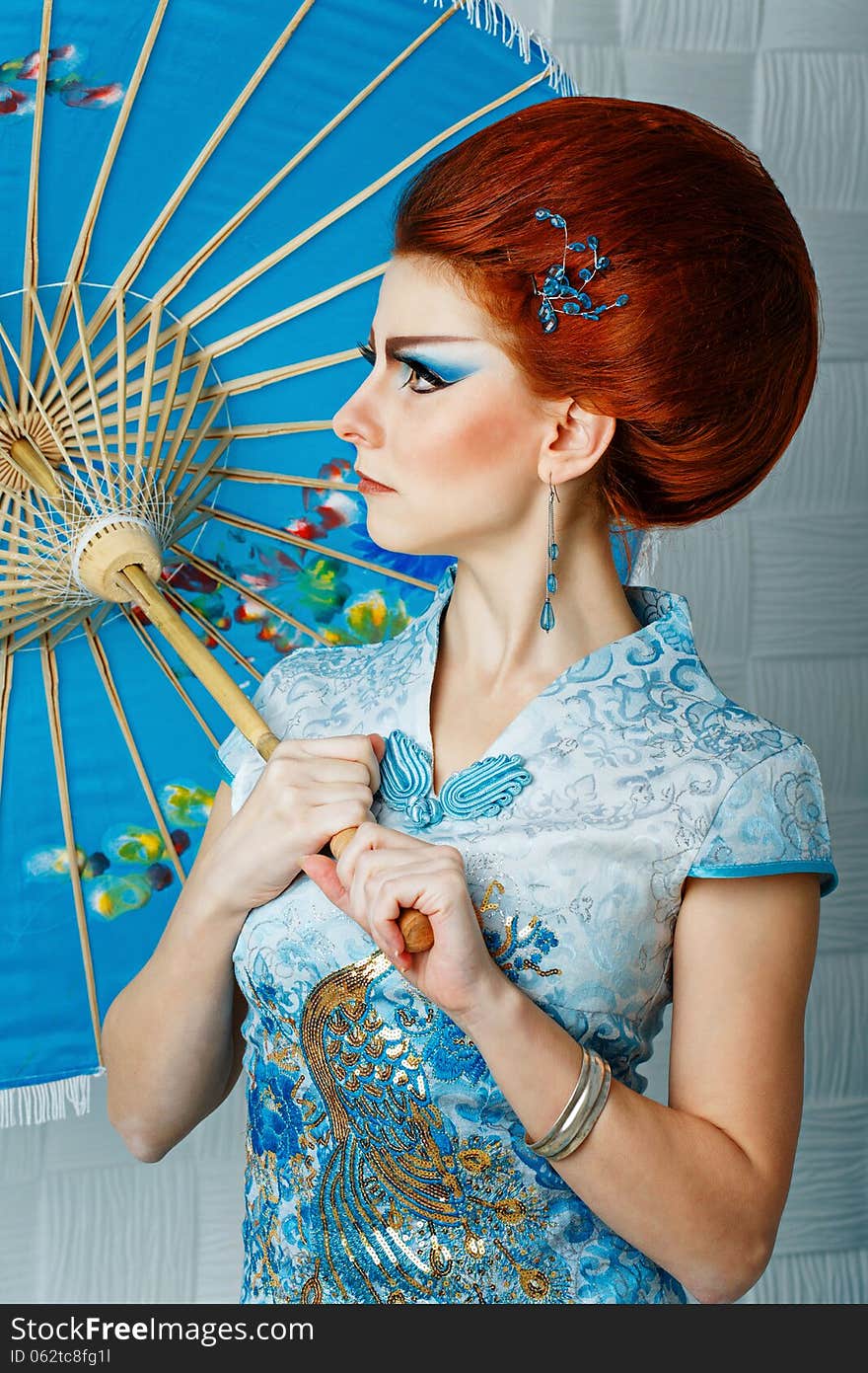 Attractive geisha in a smart dress with an umbrella, photographed in the studio. Attractive geisha in a smart dress with an umbrella, photographed in the studio