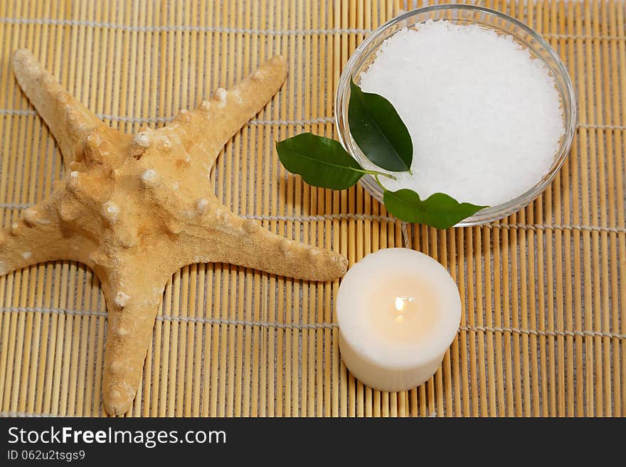 Spa still life - Sea star, candle and sea salt on bamboo mat