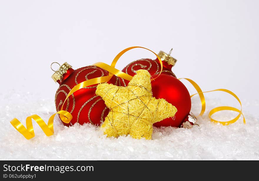 Red-golden baubles and yellow star on the snow. Red-golden baubles and yellow star on the snow