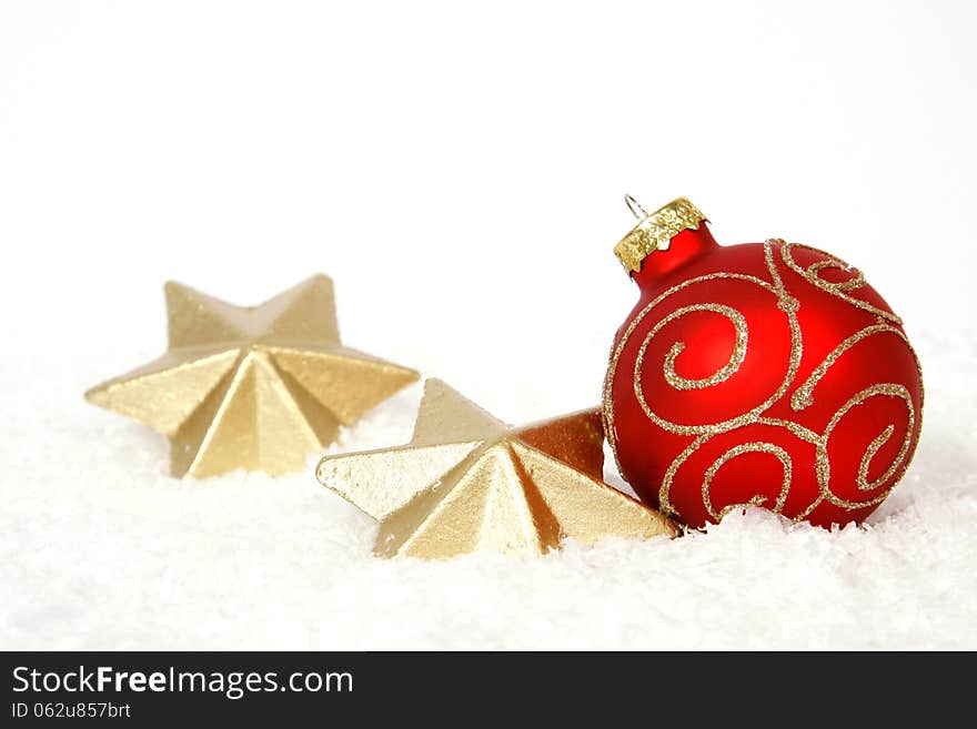 Red-golden bauble and golden stars on the snow. Red-golden bauble and golden stars on the snow