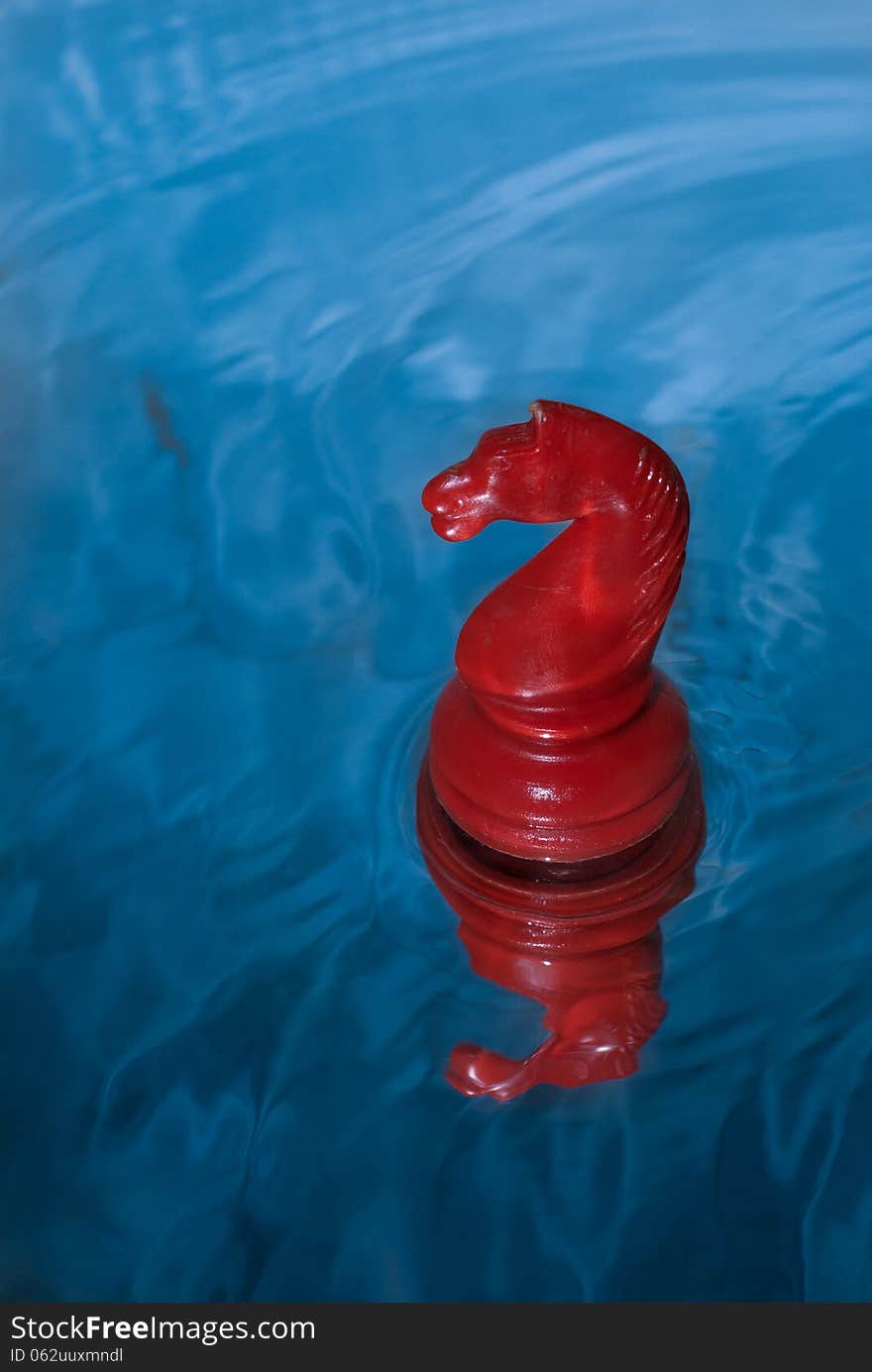 Red chess knight floating on water