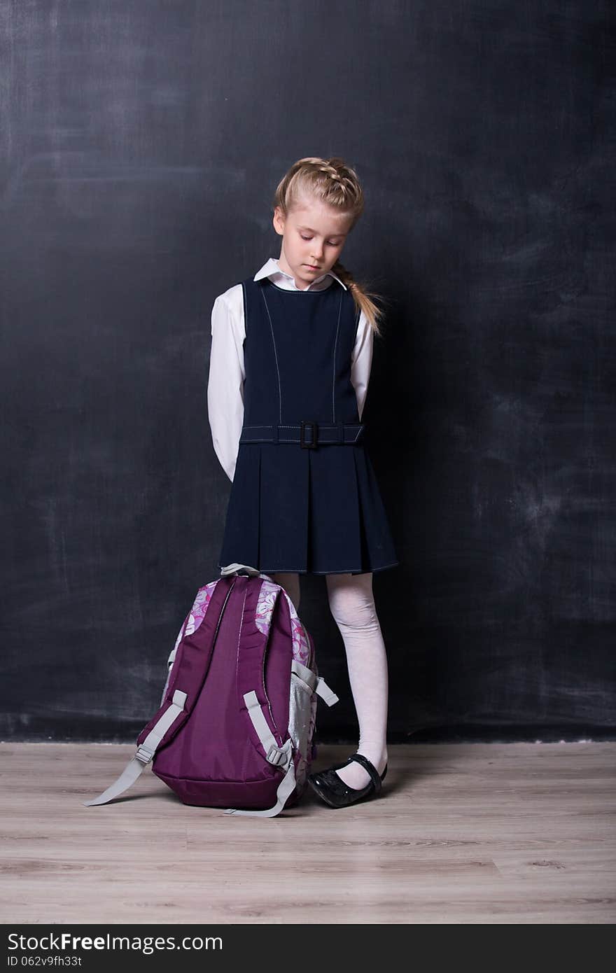 Latecomers little schoolgirl with backpack near blackboard